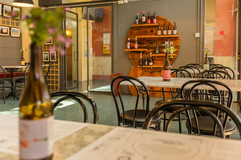 Detall interior de La Taverna de l'Escorxador amb una estanteria circular de fusta i ampolles de vi de proximitat, espai de formació en hostaleria a Vilafranca del Penedès.